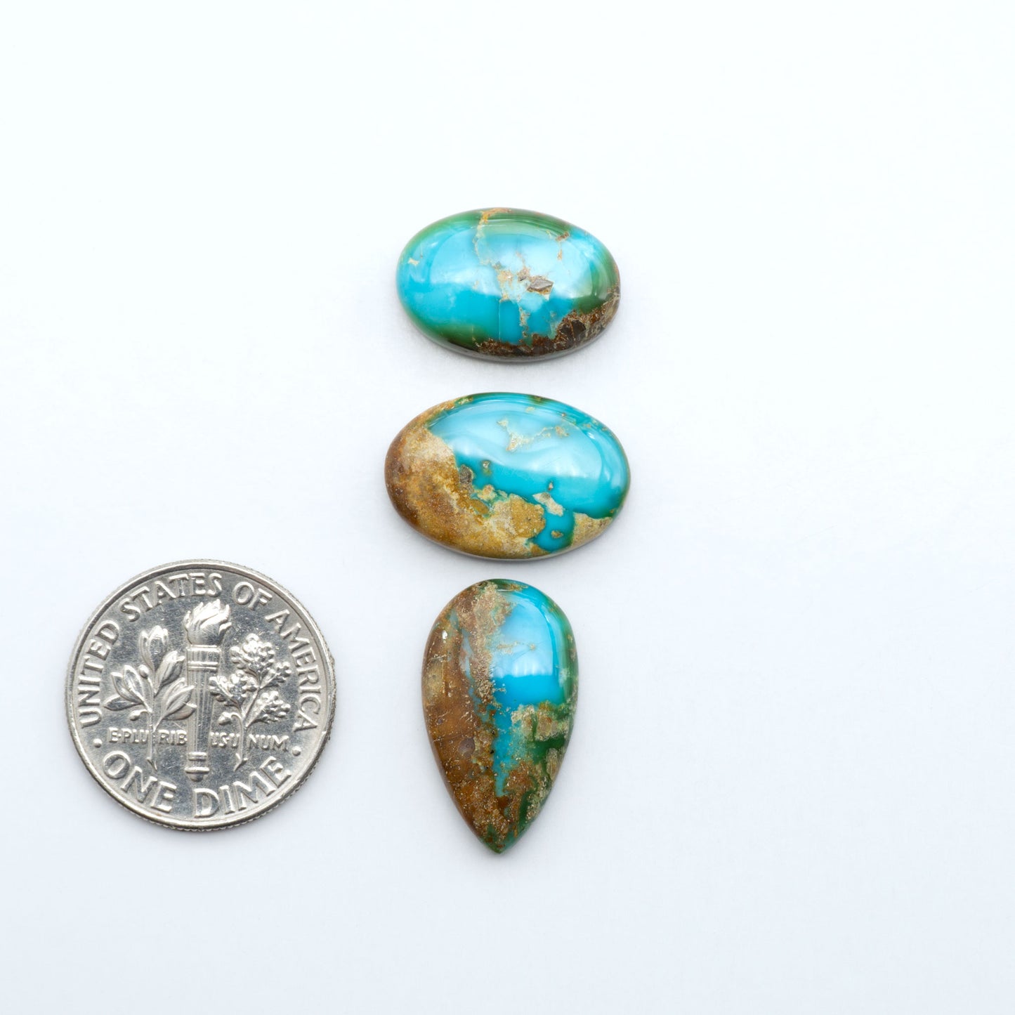 Sonoran Mountain Turquoise cabochons, blue-green color with natural matrix, polished stones on a white background, with a US dime for scale