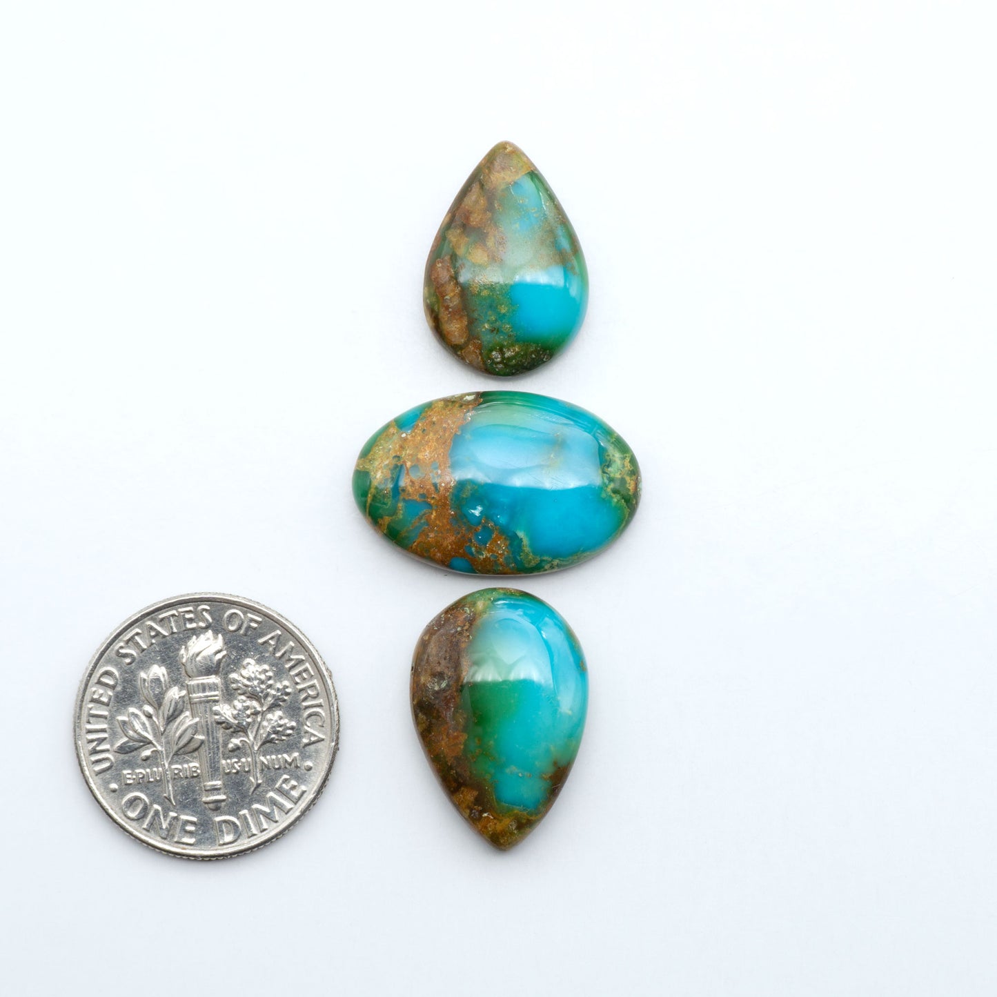 Sonoran Mountain Turquoise cabochons, blue-green color with natural matrix, polished stones on a white background, with a US dime for scale