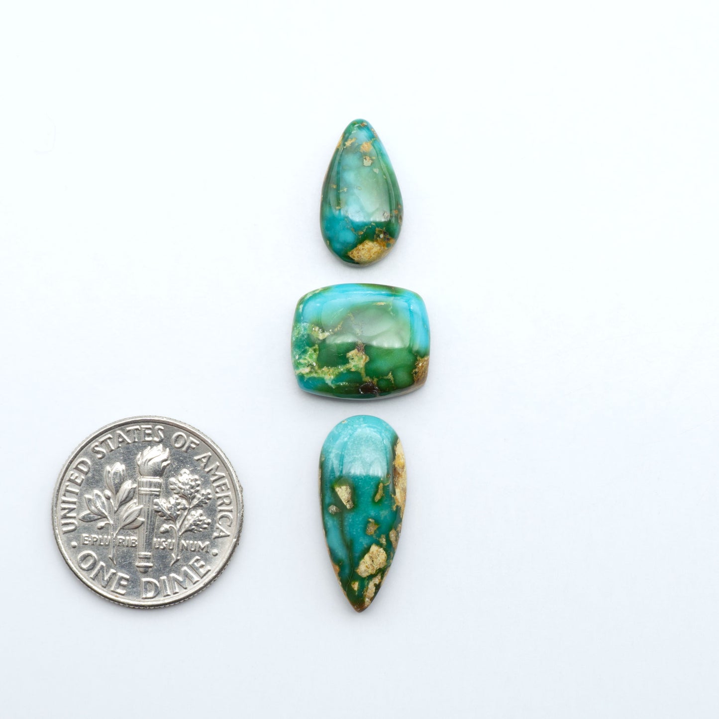 Sonoran Mountain Turquoise cabochons, blue-green color with natural matrix, polished stones on a white background, with a US dime for scale