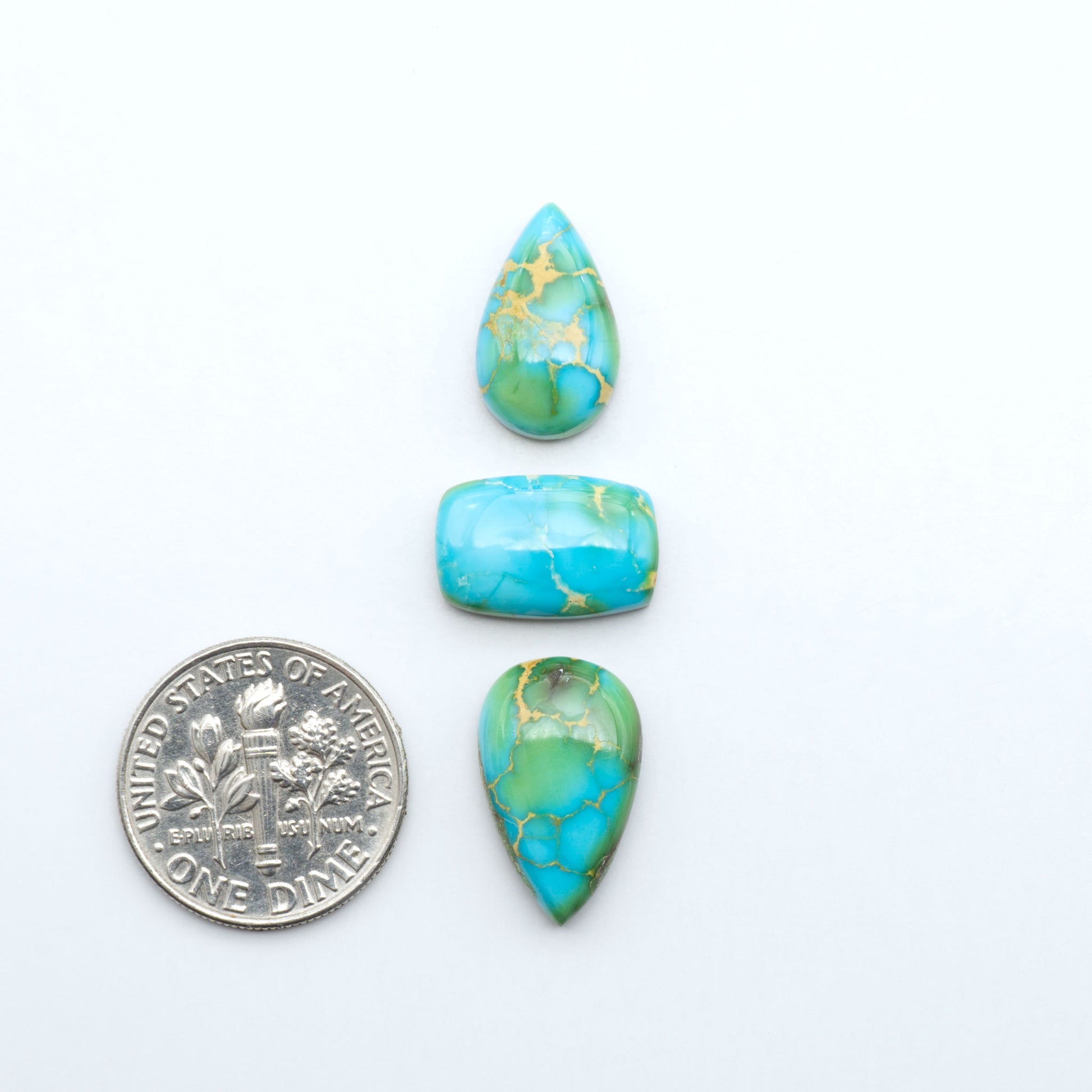 Sonoran Mountain Turquoise cabochons, blue-green color with natural matrix, polished stones on a white background, with a US dime for scale