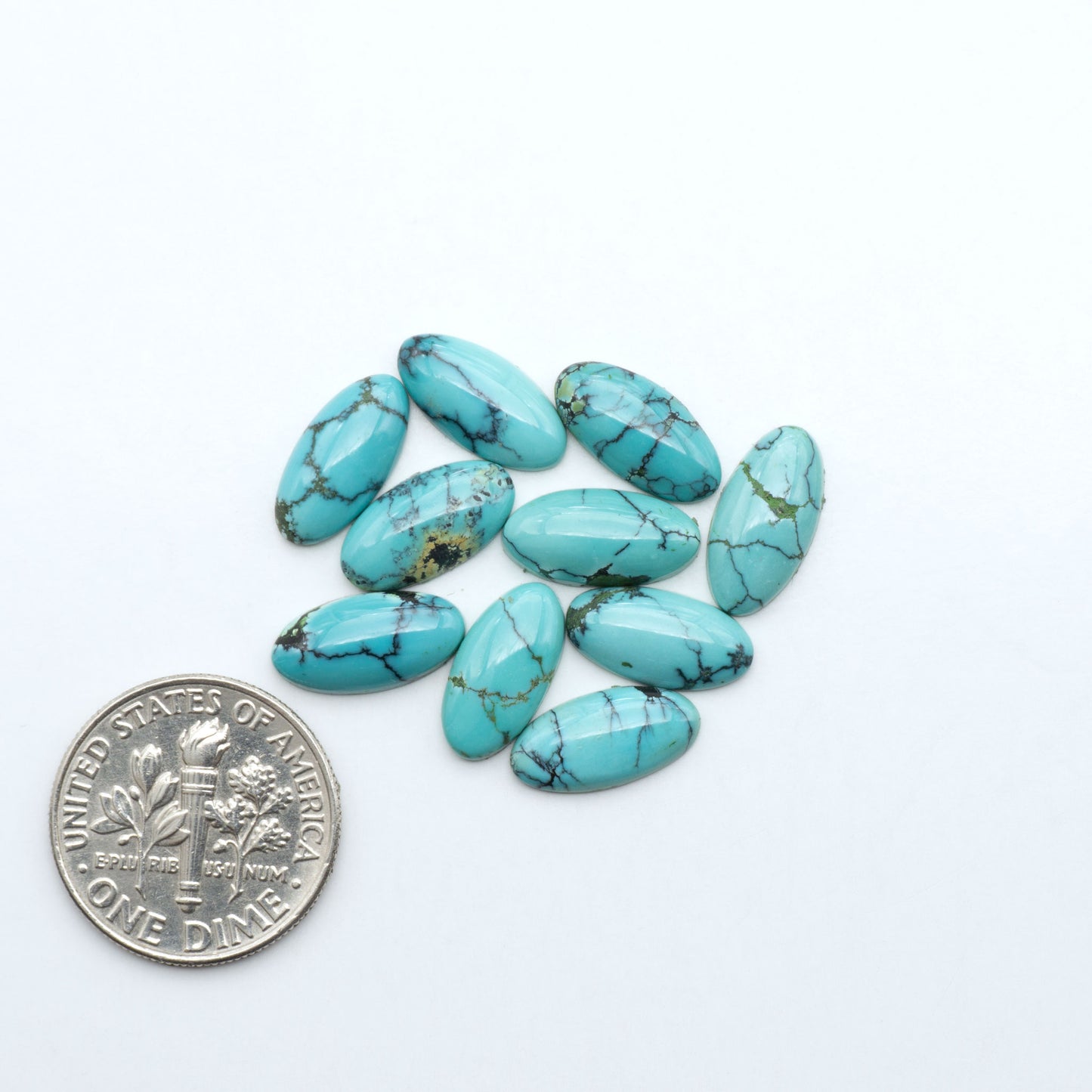 Hubei Cloud Mountain Turquoise cabochons, blue and green color with black matrix, polished stones on a white background with a US dime for scale
