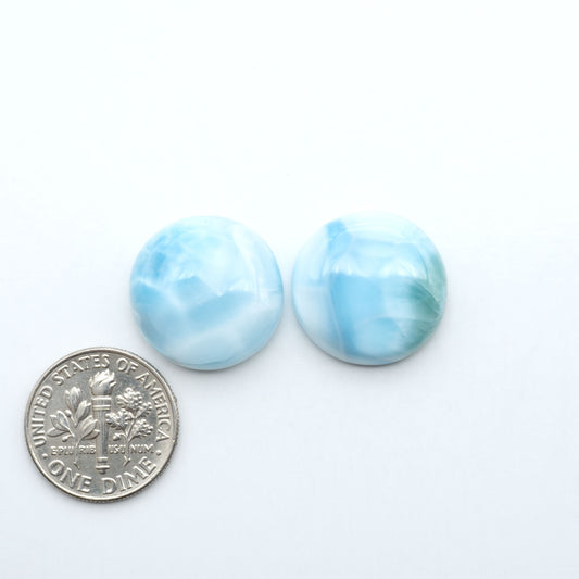 Larimar stone cabochons, cut and polished, blue and white gemstones on a white background, with a US dime for scale
