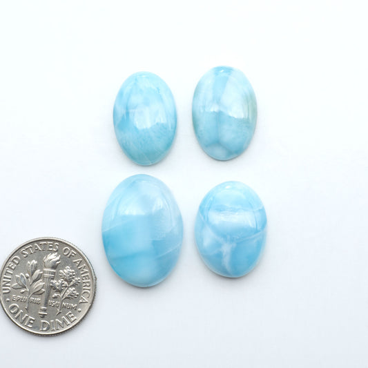 Larimar stone cabochons, cut and polished, blue and white gemstones on a white background, with a US dime for scale