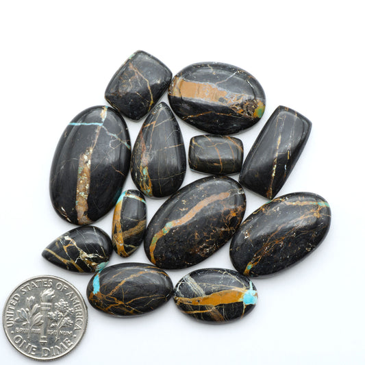 Black Jack turquoise cabochons, blue-green color with black matrix, polished stones on a white background with a US dime for scale