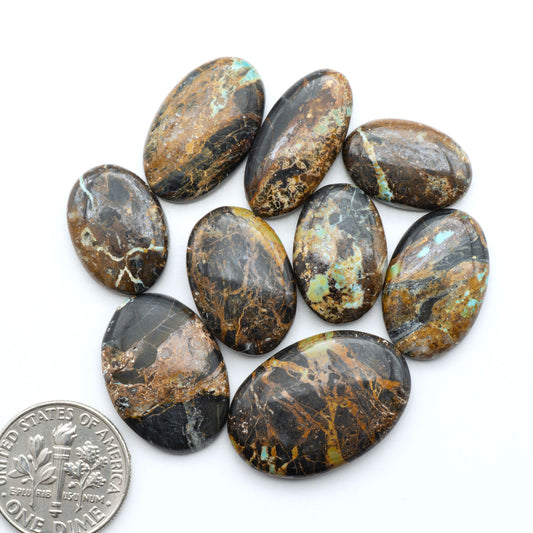 Black Jack turquoise cabochons, blue-green color with black matrix, polished stones on a white background with a US dime for scale
