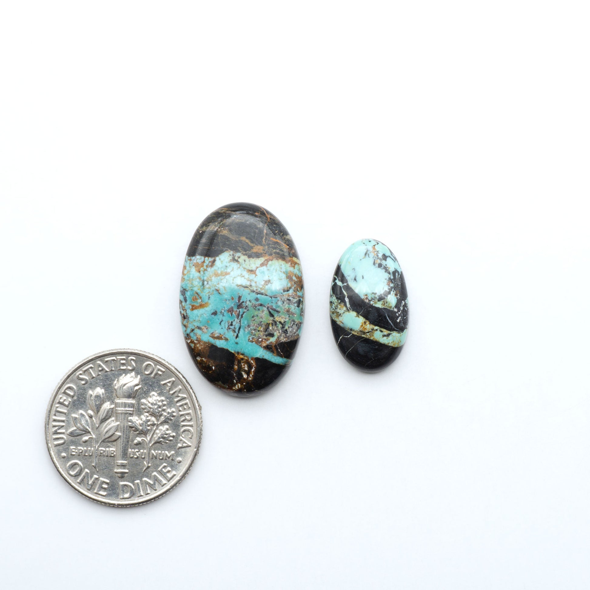 Black Jack turquoise cabochons, blue-green color with black matrix, polished stones on a white background with a US dime for scale