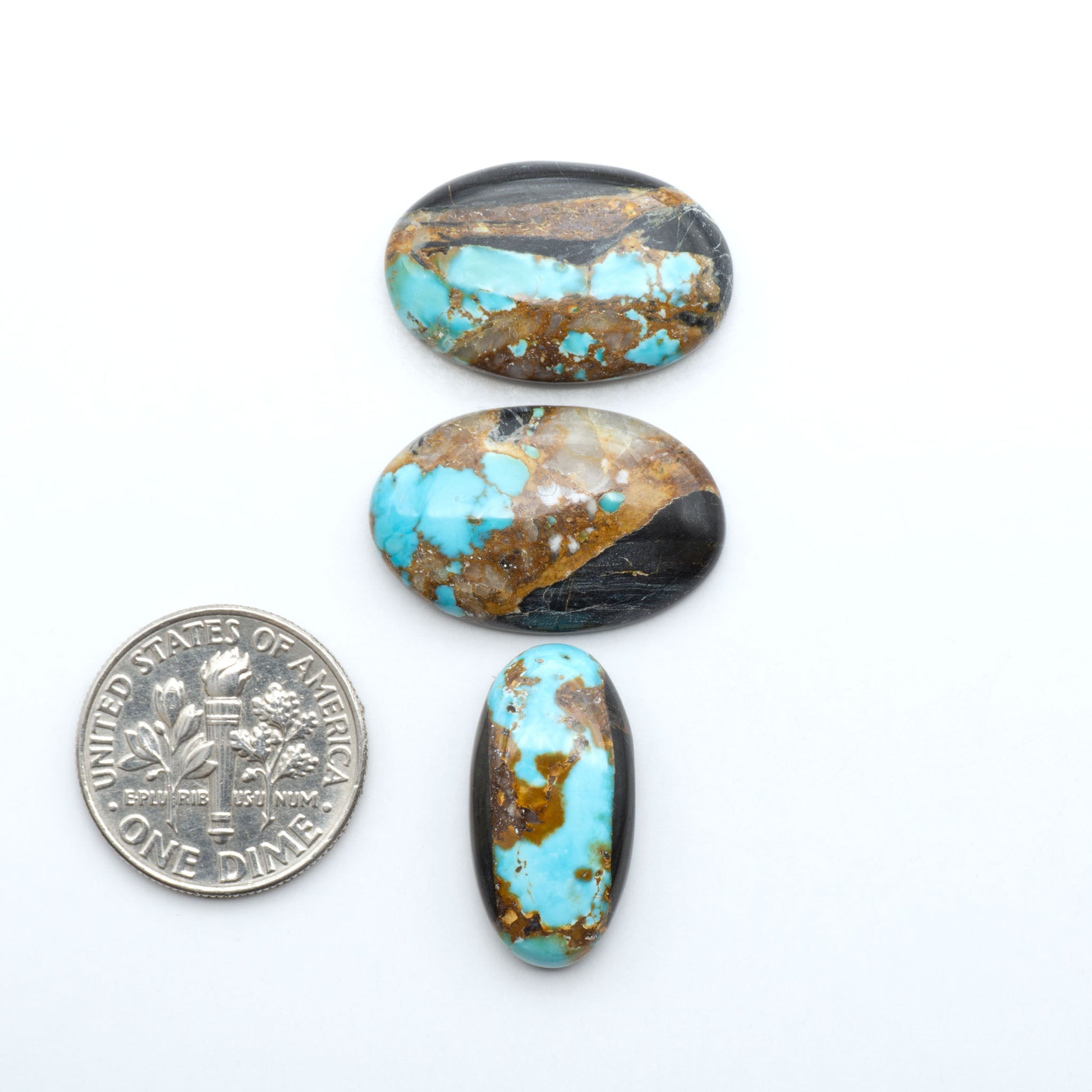 Black Jack turquoise cabochons, blue-green color with black matrix, polished stones on a white background with a US dime for scale