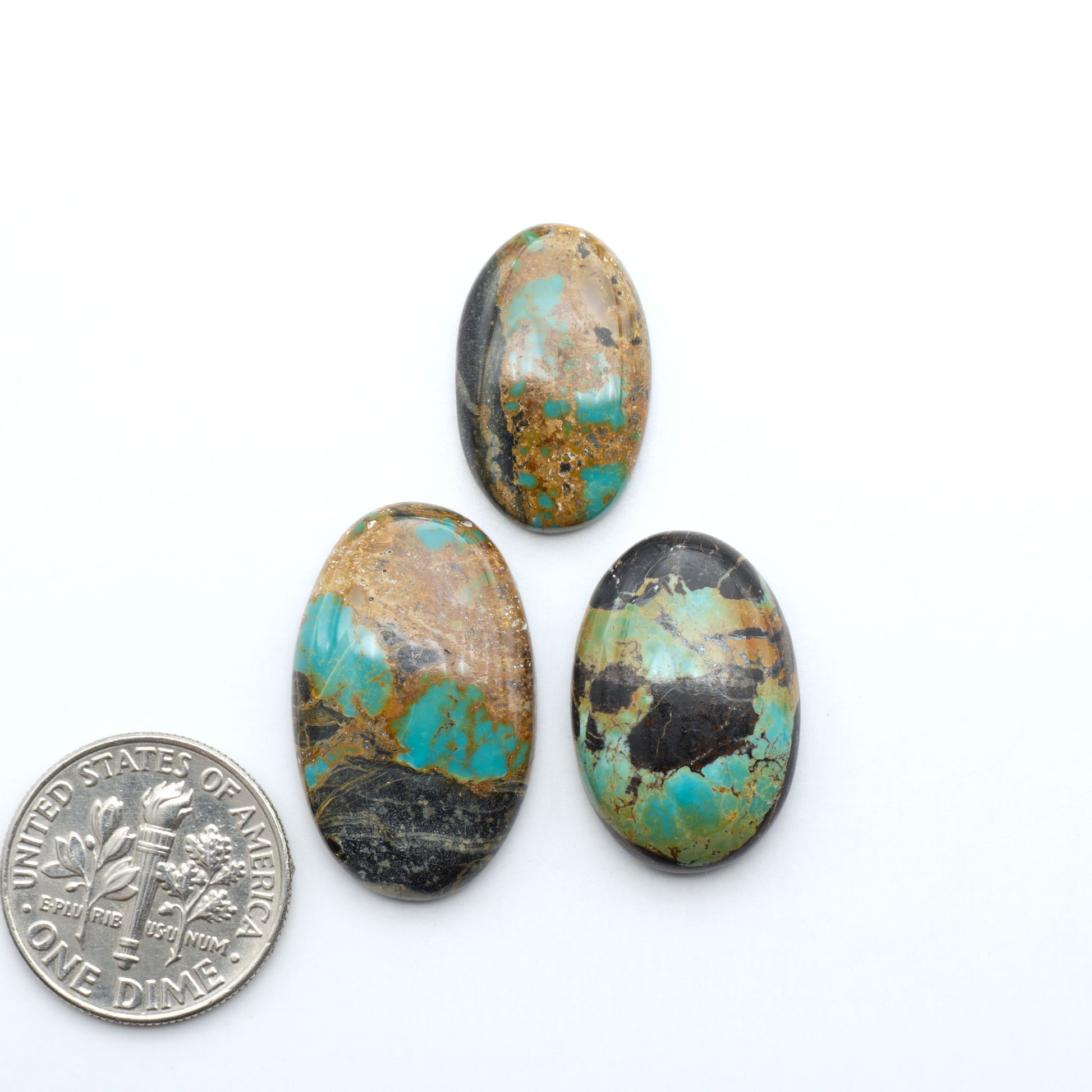 Black Jack turquoise cabochons, blue-green color with black matrix, polished stones on a white background with a US dime for scale