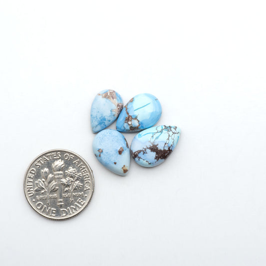 Golden Hills Turquoise cabochons, icy blue to lavender tones with chocolate matrix, polished stones on a white background with a US dime for scale