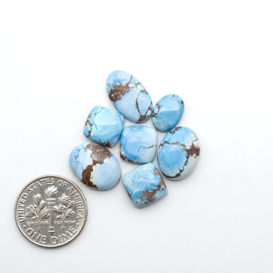 Golden Hills Turquoise cabochons, icy blue to lavender tones with chocolate matrix, polished stones on a white background with a US dime for scale