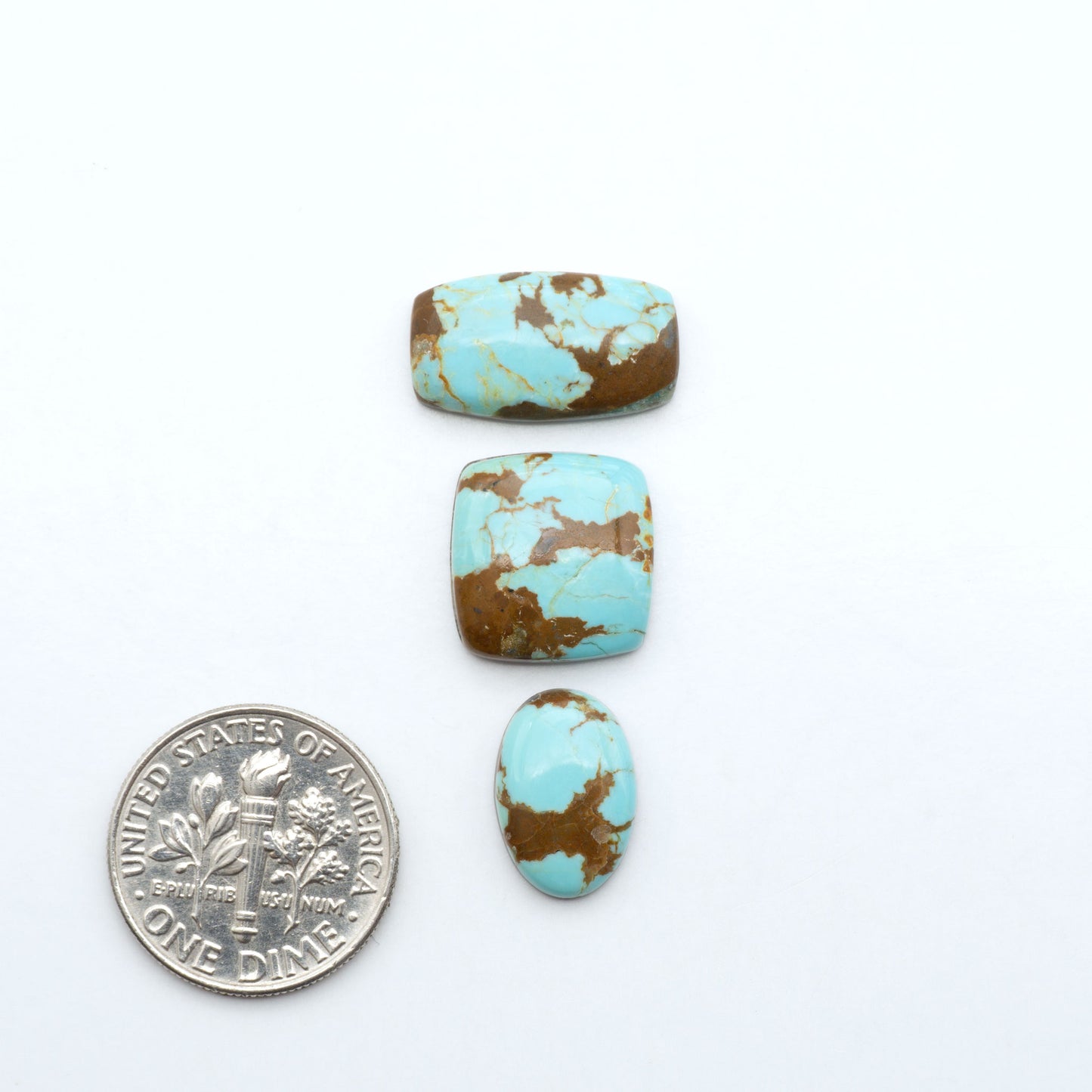 Number 8 Turquoise cabochons, blue and green color with brown matrix, polished stones on a white background, with a US dime for scale