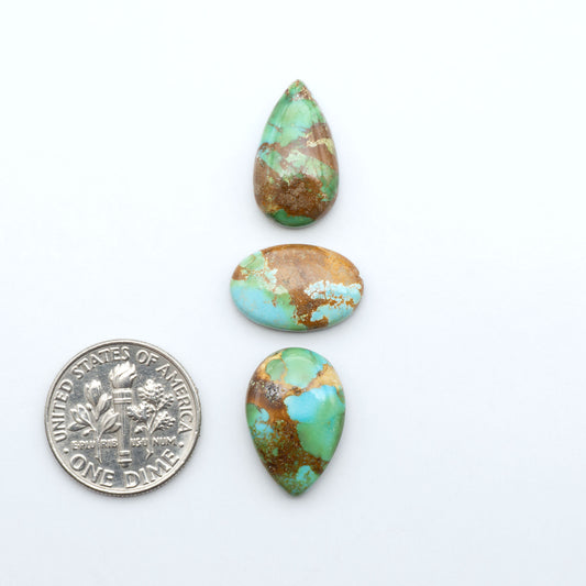 Sonoran Mountain Turquoise cabochons, blue-green color with natural matrix, polished stones on a white background, with a US dime for scale