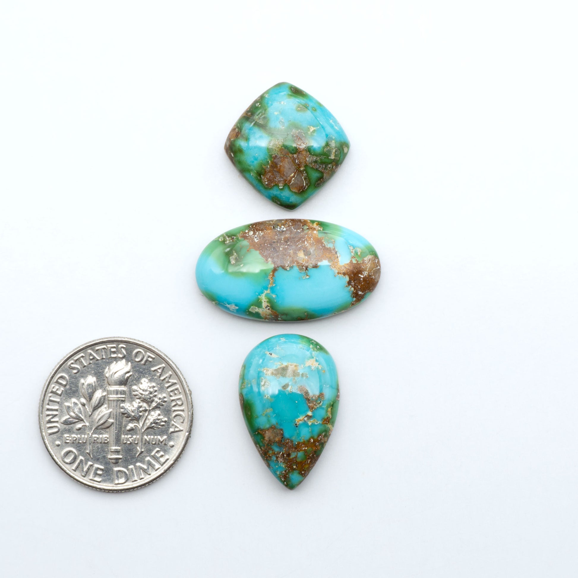 Sonoran Mountain Turquoise cabochons, blue-green color with natural matrix, polished stones on a white background, with a US dime for scale