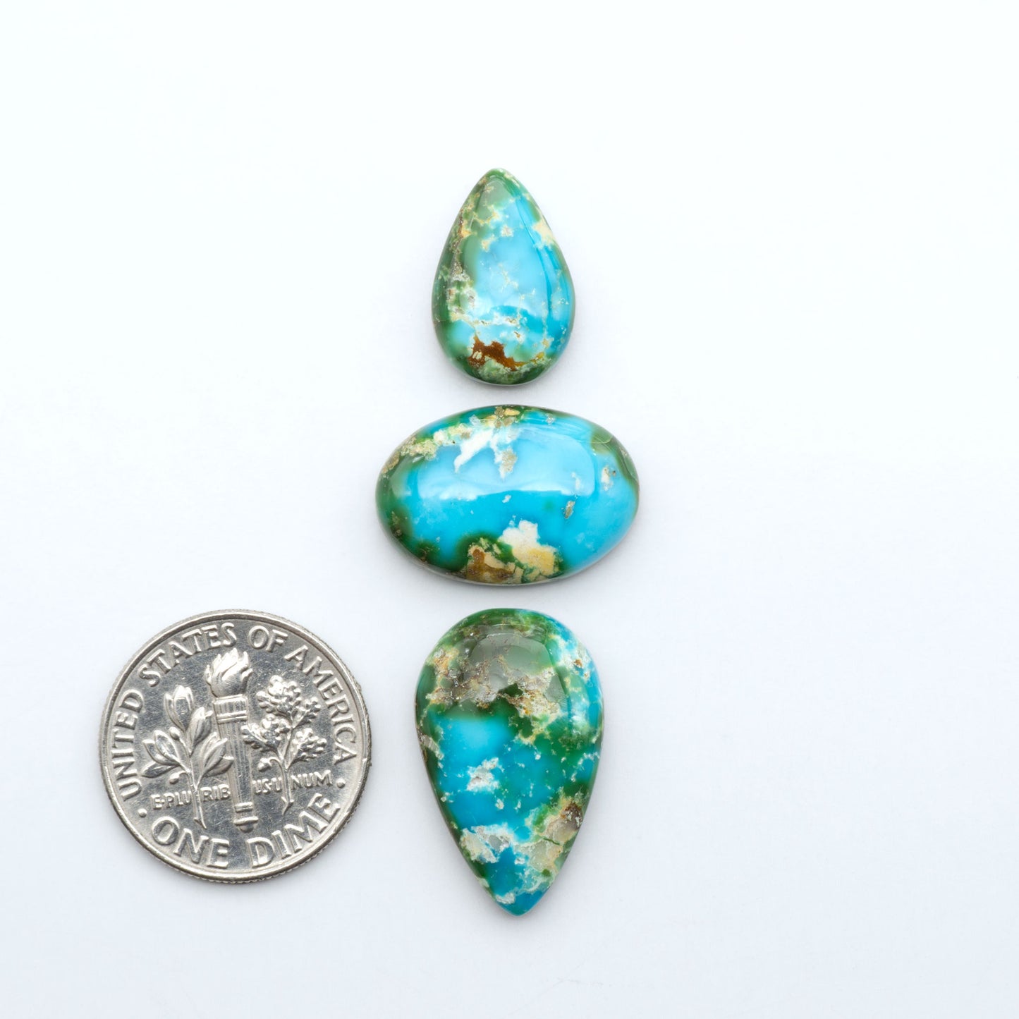 Sonoran Mountain Turquoise cabochons, blue-green color with natural matrix, polished stones on a white background, with a US dime for scale