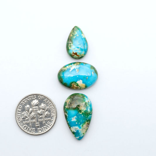Sonoran Mountain Turquoise cabochons, blue-green color with natural matrix, polished stones on a white background, with a US dime for scale