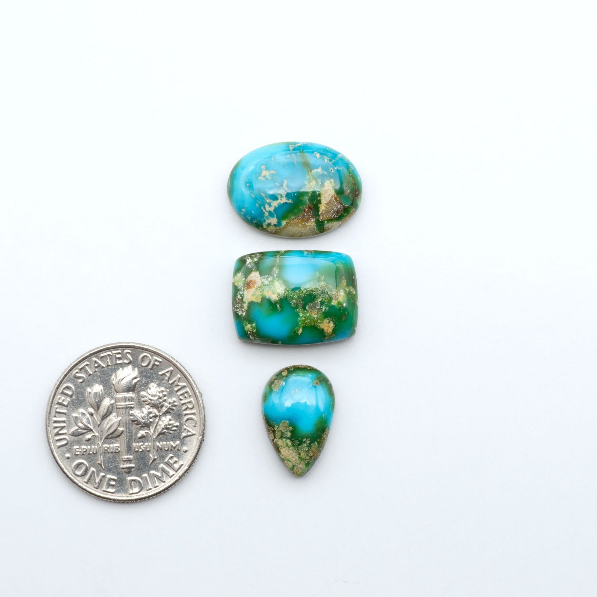 Sonoran Mountain Turquoise cabochons, blue-green color with natural matrix, polished stones on a white background, with a US dime for scale