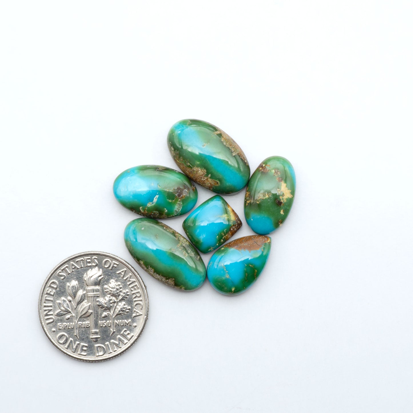Sonoran Mountain Turquoise cabochons, blue-green color with natural matrix, polished stones on a white background, with a US dime for scale