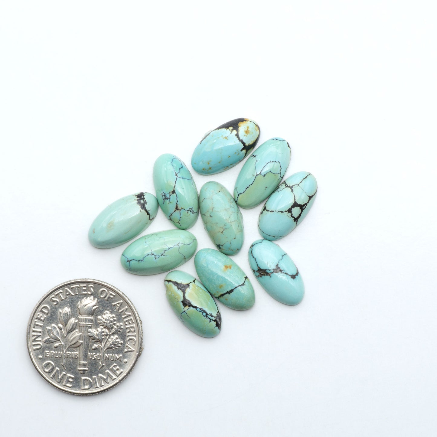 Hubei Cloud Mountain Turquoise cabochons, blue and green color with black matrix, polished stones on a white background with a US dime for scale