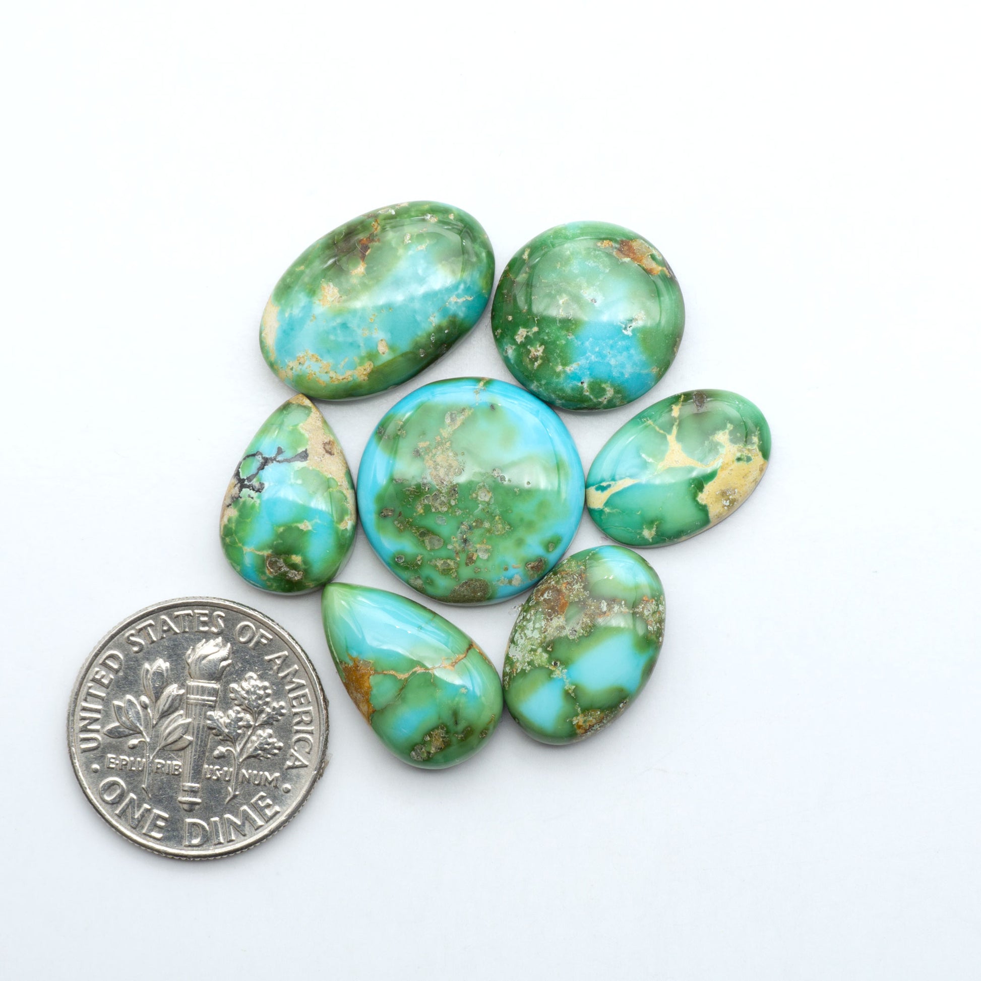 Sonoran Mountain Turquoise cabochons, blue-green color with natural matrix, polished stones on a white background, with a US dime for scale