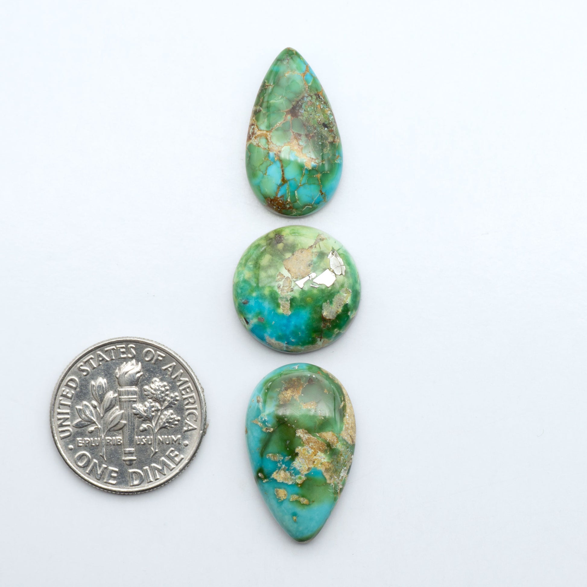 Sonoran Mountain Turquoise cabochons, blue-green color with natural matrix, polished stones on a white background, with a US dime for scale