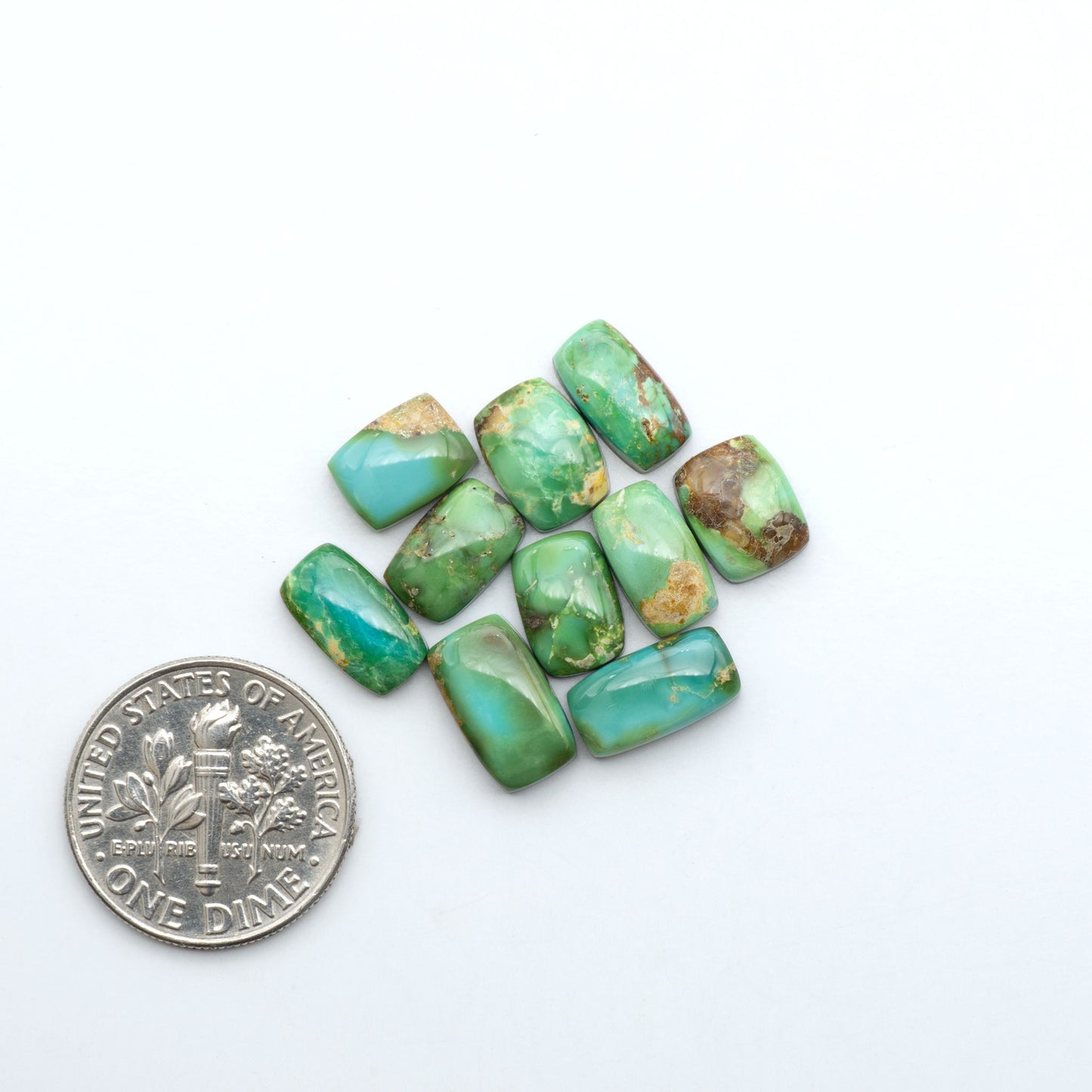 Sonoran Mountain Turquoise cabochons, blue-green color with natural matrix, polished stones on a white background, with a US dime for scale