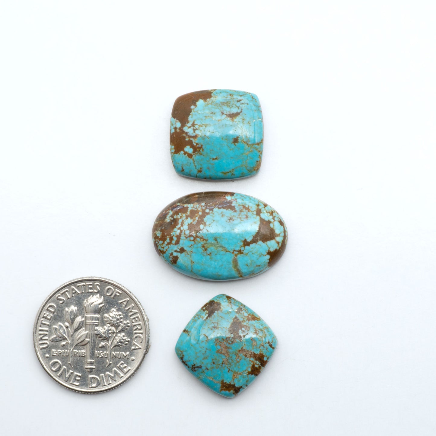 Number 8 Turquoise cabochons, blue and green color with brown matrix, polished stones on a white background, with a US dime for scale
