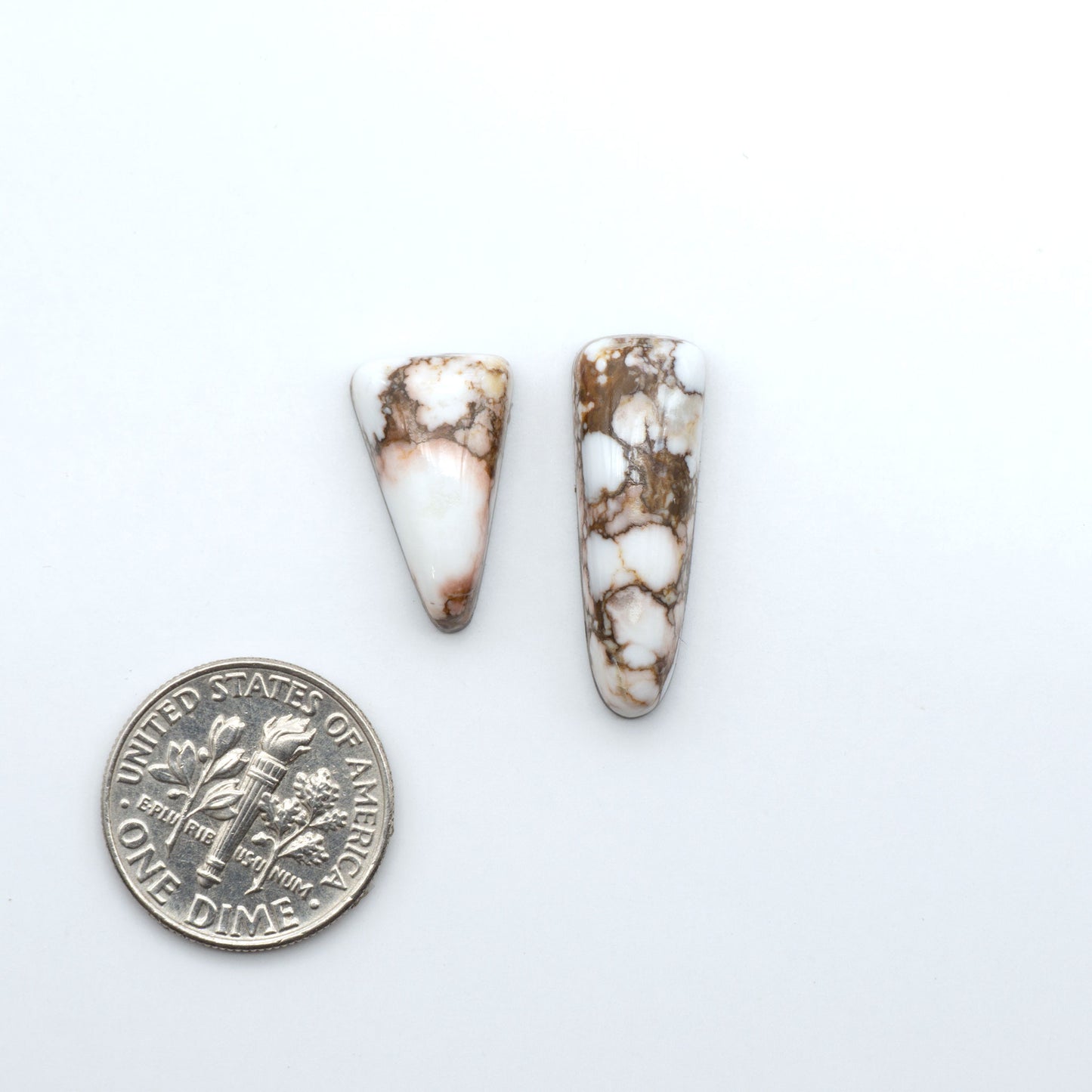 Wild Horse Magnesite cabochons, white gemstones with brown matrix on a white background, with a US dime for scale