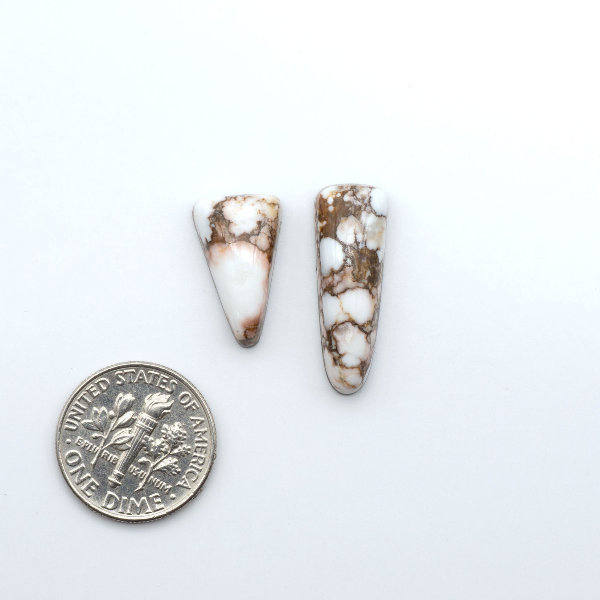 Wild Horse Magnesite cabochons, white gemstones with brown matrix on a white background, with a US dime for scale
