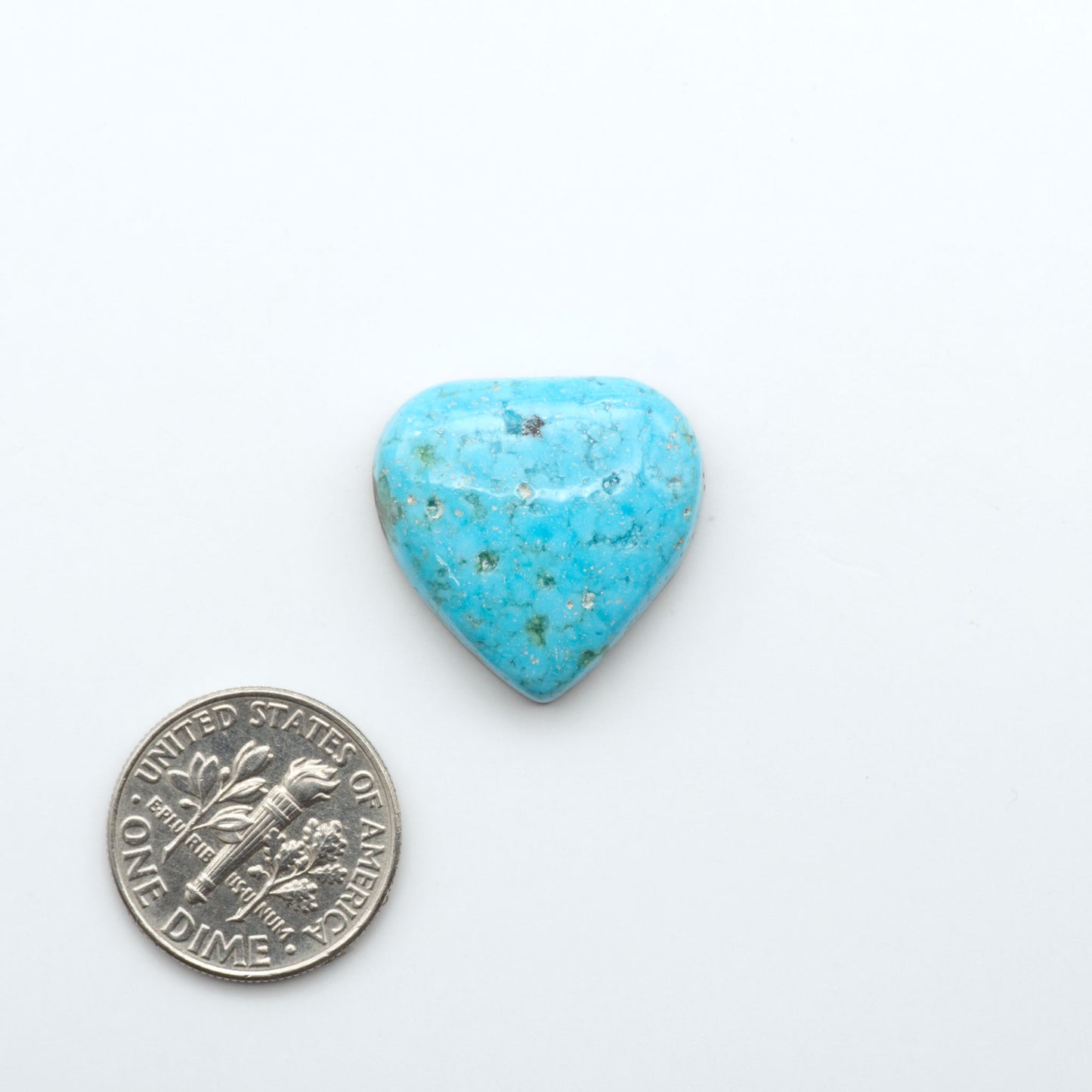 Nacozari Turquoise cabochons, blue to greenish-blue gemstones with black or brown matrix and pyrite on a white background with a US dime for scale