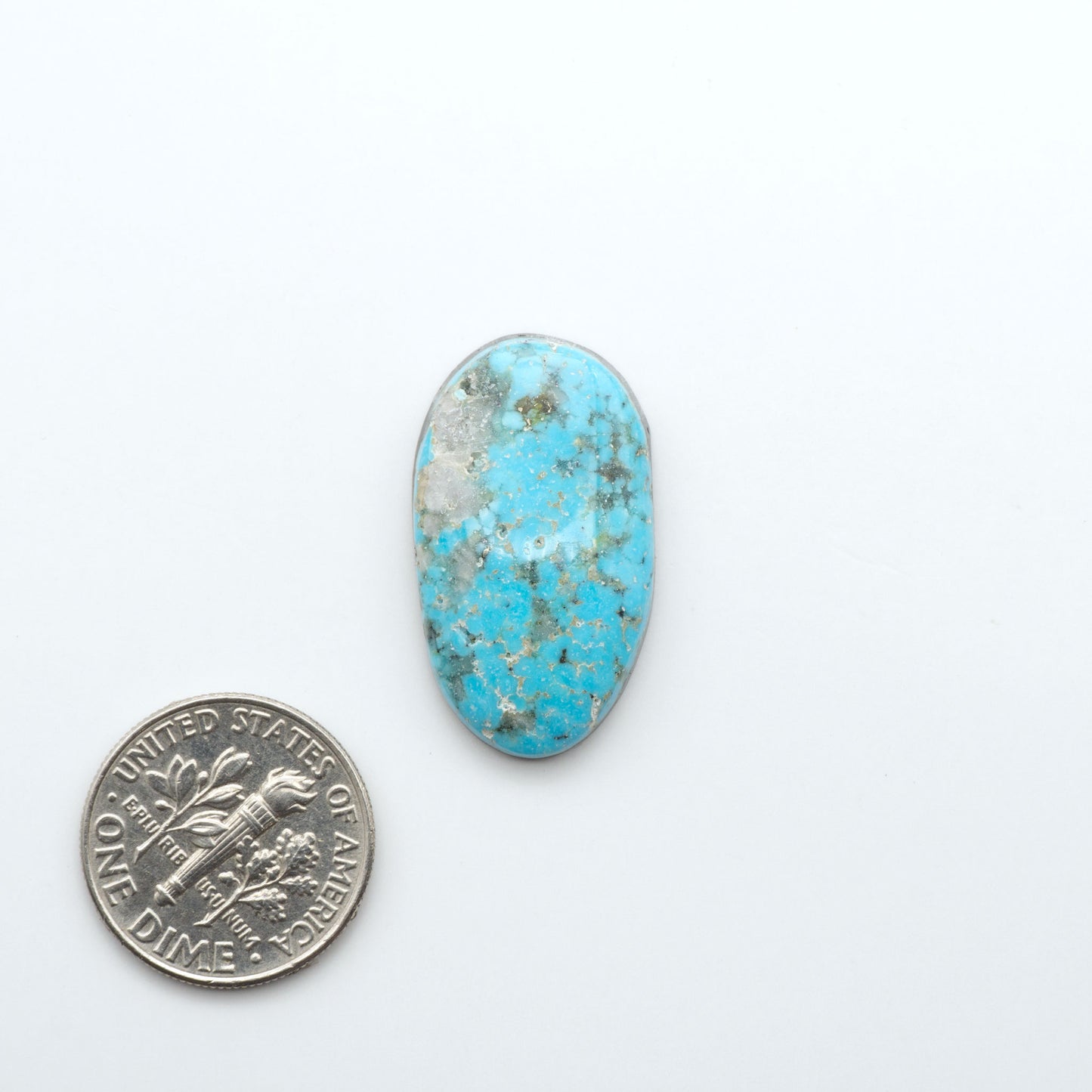 Nacozari Turquoise cabochons, blue to greenish-blue gemstones with black or brown matrix and pyrite on a white background with a US dime for scale