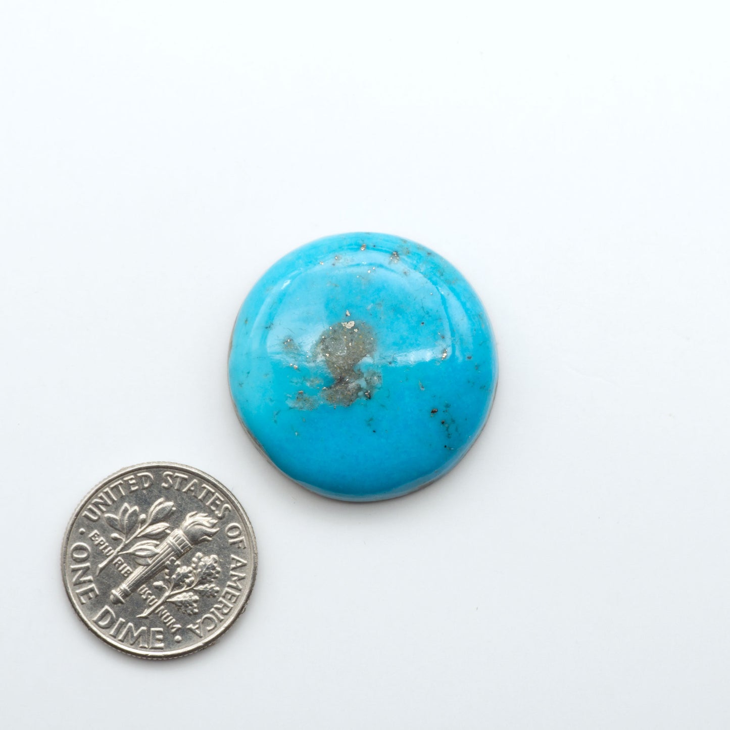 Nacozari Turquoise cabochons, blue to greenish-blue gemstones with black or brown matrix and pyrite on a white background with a US dime for scale
