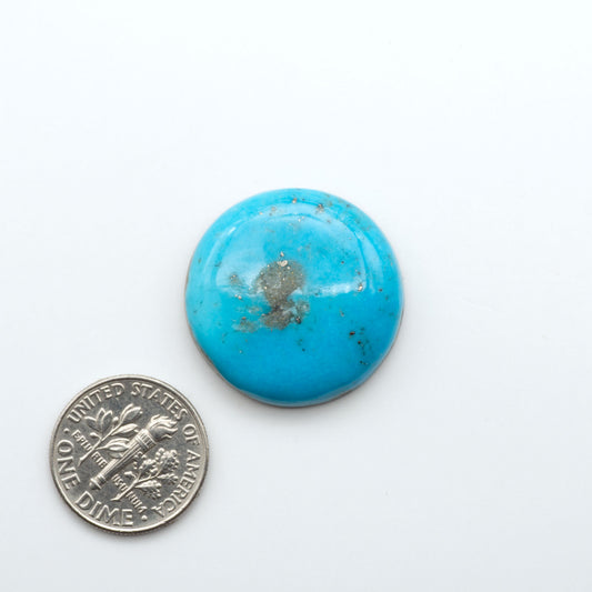Nacozari Turquoise cabochons, blue to greenish-blue gemstones with black or brown matrix and pyrite on a white background with a US dime for scale