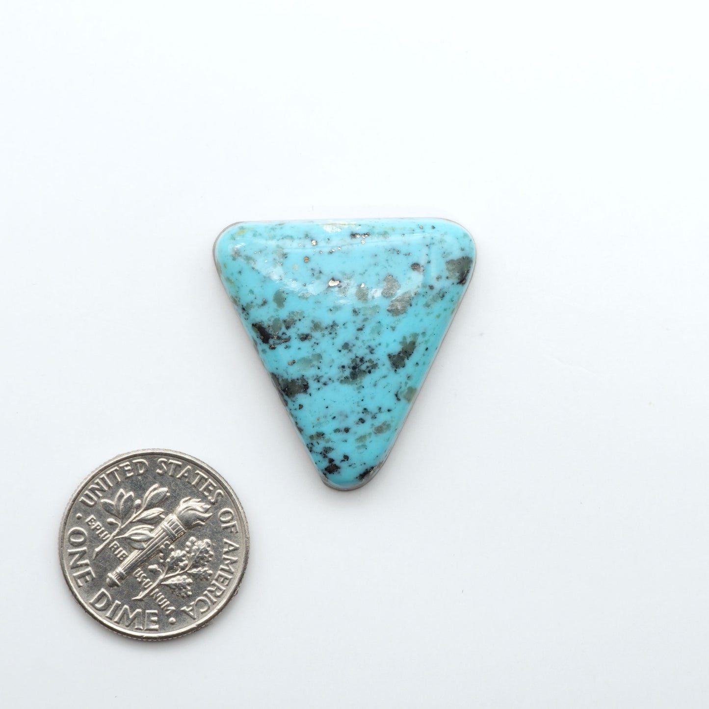 Nacozari Turquoise cabochons, blue to greenish-blue gemstones with black or brown matrix and pyrite on a white background with a US dime for scale