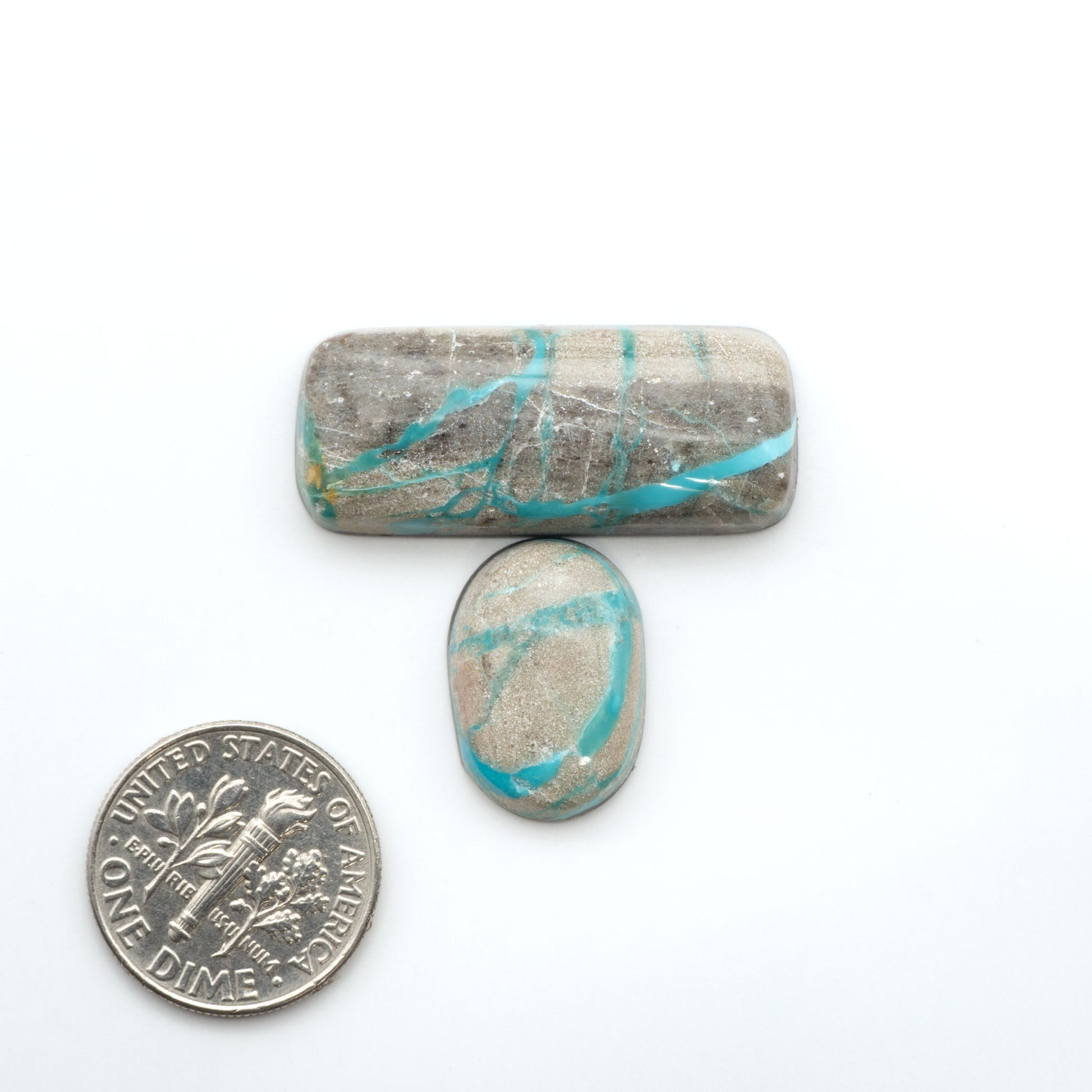 Carico Lake Turquoise cabochons, aqua-blue to turquoise gemstones with natural matrix on a white background with a US dime for scale