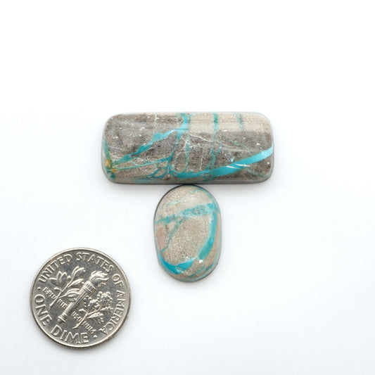 Carico Lake Turquoise cabochons, aqua-blue to turquoise gemstones with natural matrix on a white background with a US dime for scale