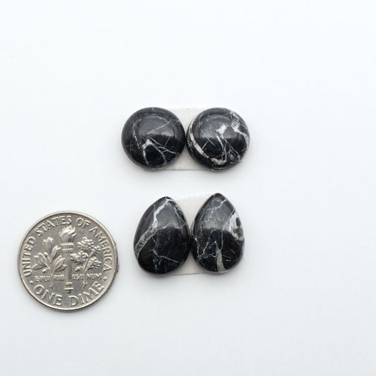 White Buffalo stone cabochons, white stone with black matrix, polished stones on a white background, with a US dime for scale