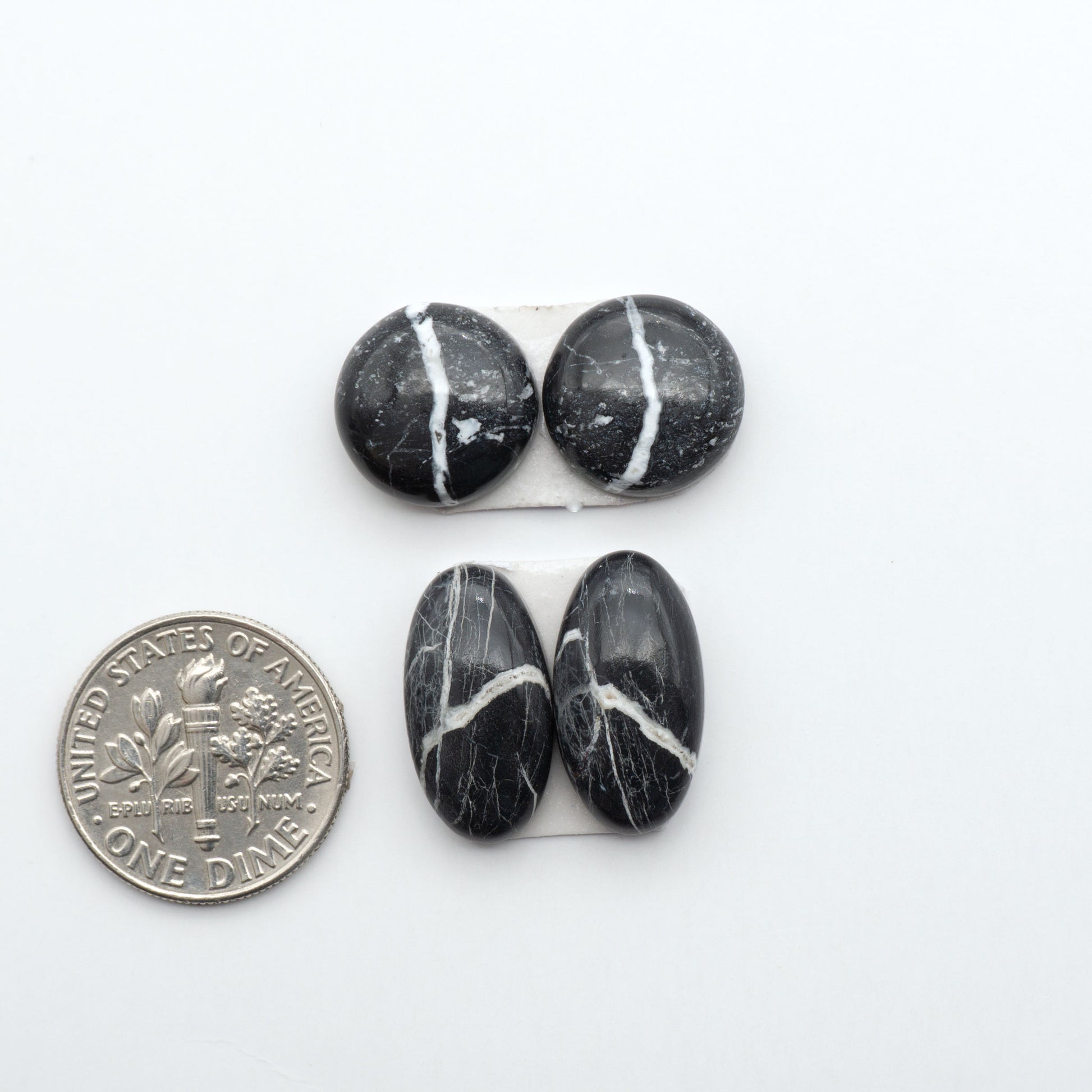 White Buffalo stone cabochons, white stone with black matrix, polished stones on a white background, with a US dime for scale