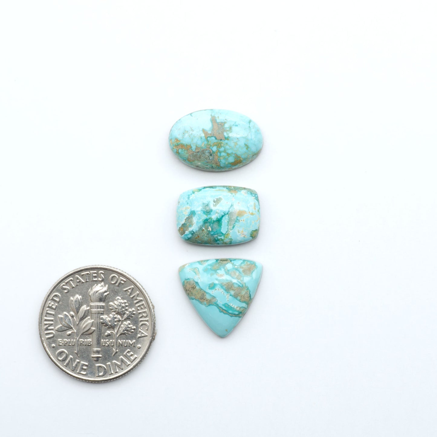 Fox Turquoise cabochons, polished gemstones with natural matrix on a white background, with a US dime for scale