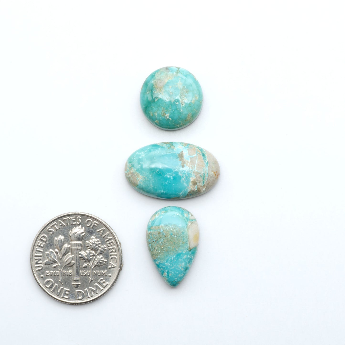 Fox Turquoise cabochons, polished gemstones with natural matrix on a white background, with a US dime for scale