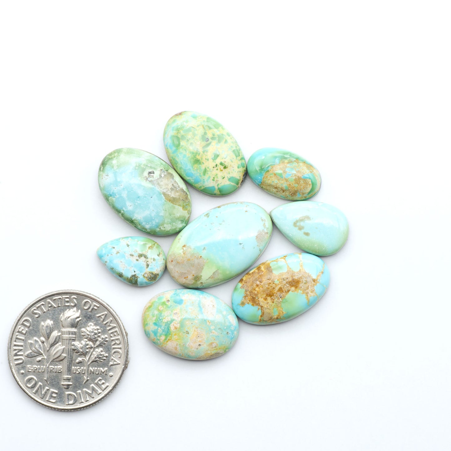 Sonoran Mountain Turquoise cabochons, blue-green color with natural matrix, polished stones on a white background, with a US dime for scale