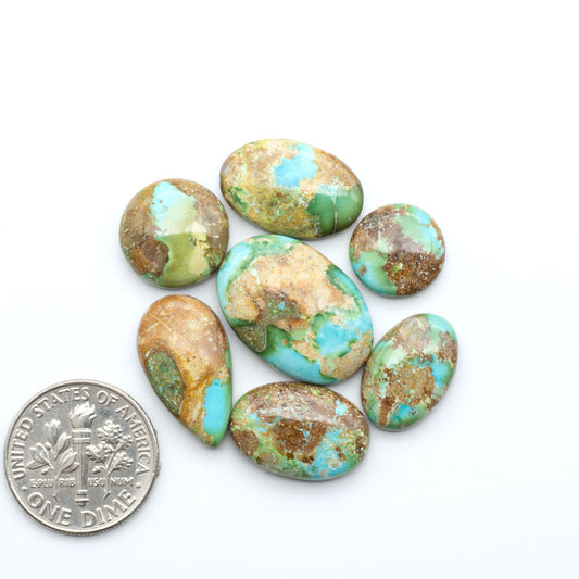 Sonoran Mountain Turquoise cabochons, blue-green color with natural matrix, polished stones on a white background, with a US dime for scale