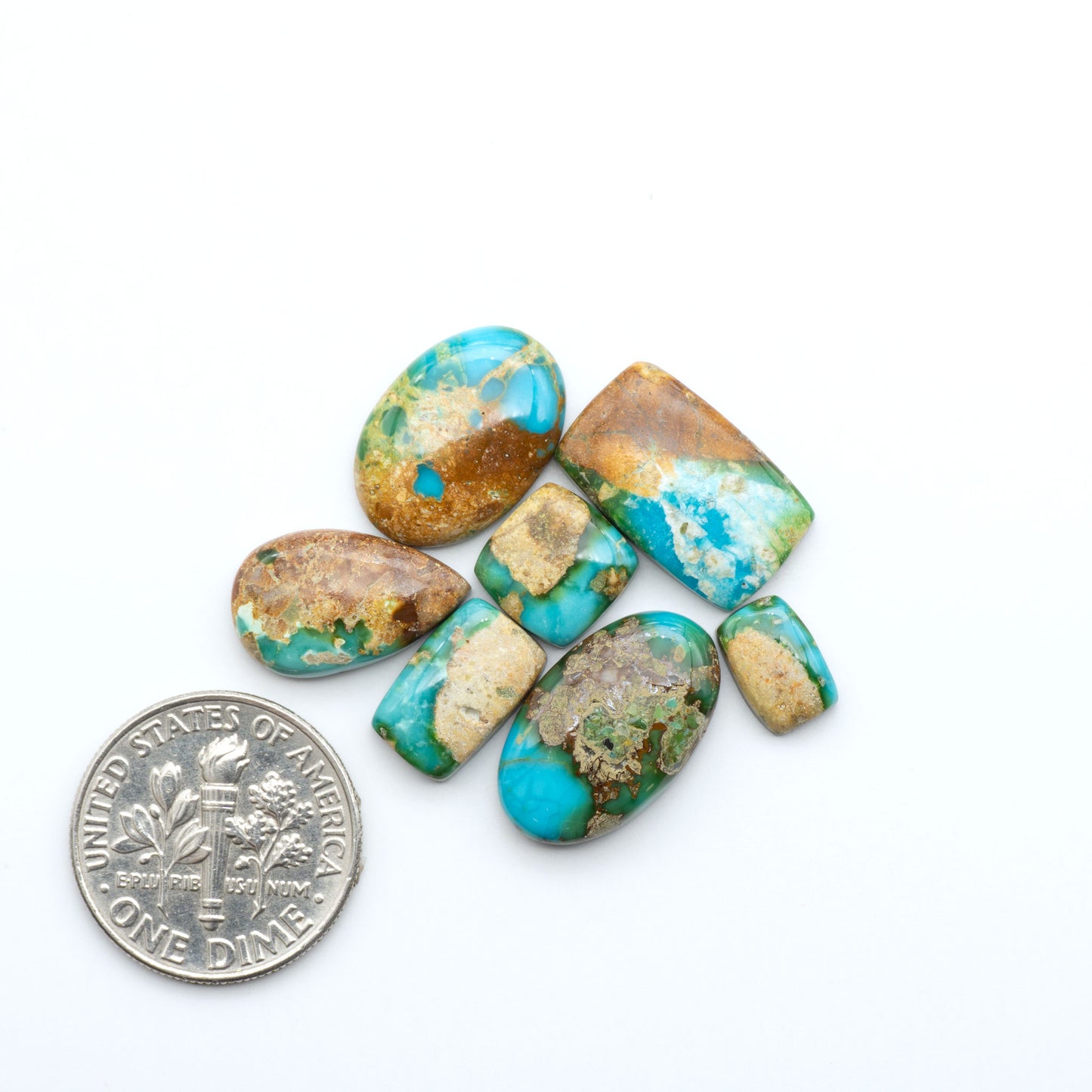 Sonoran Mountain Turquoise cabochons, blue-green color with natural matrix, polished stones on a white background, with a US dime for scale