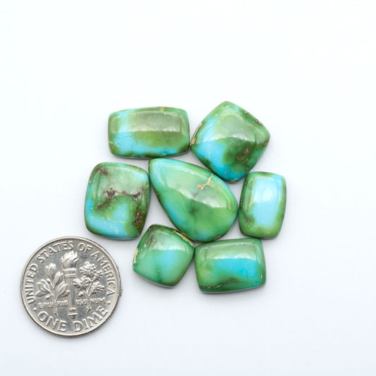 Sonoran Mountain Turquoise cabochons, blue-green color with natural matrix, polished stones on a white background, with a US dime for scale