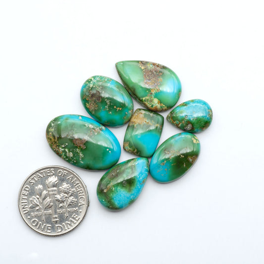 Sonoran Mountain Turquoise cabochons, blue-green color with natural matrix, polished stones on a white background, with a US dime for scale