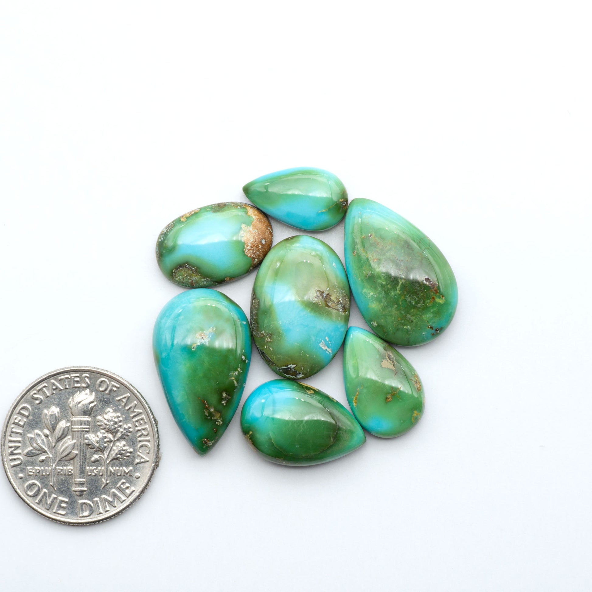 Sonoran Mountain Turquoise cabochons, blue-green color with natural matrix, polished stones on a white background, with a US dime for scale