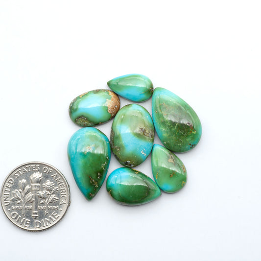 Sonoran Mountain Turquoise cabochons, blue-green color with natural matrix, polished stones on a white background, with a US dime for scale