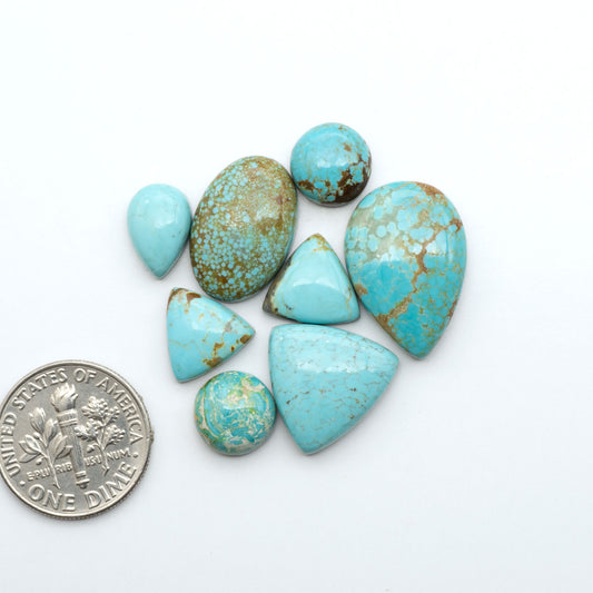 Number 8 Turquoise cabochons, blue and green color with brown matrix, polished stones on a white background, with a US dime for scale
