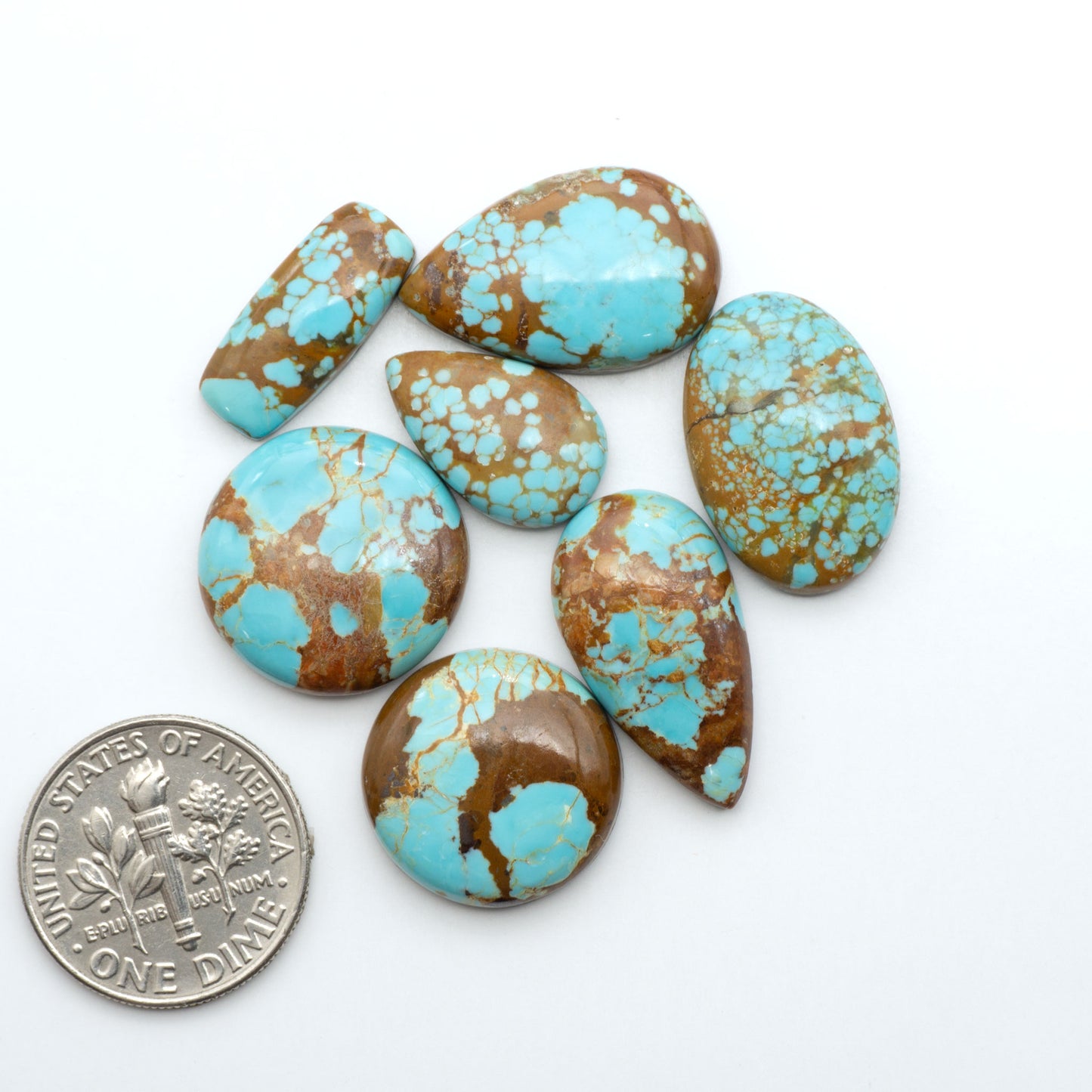 Number 8 Turquoise cabochons, blue and green color with brown matrix, polished stones on a white background, with a US dime for scale