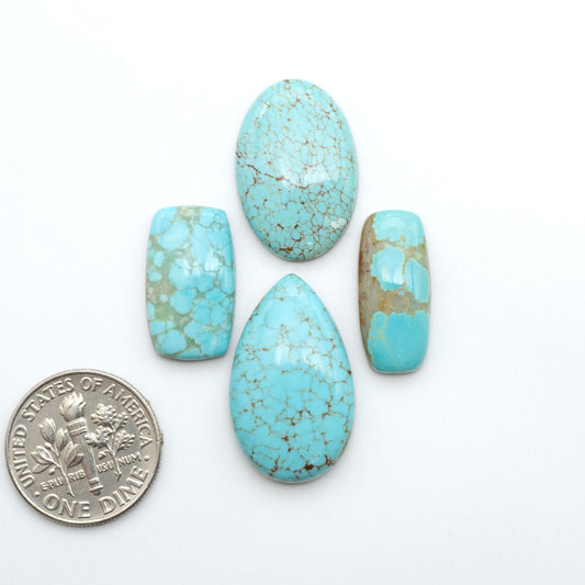 Number 8 Turquoise cabochons, blue and green color with brown matrix, polished stones on a white background, with a US dime for scale