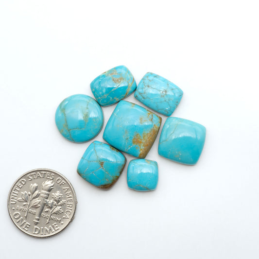 Number 8 Turquoise cabochons, blue and green color with brown matrix, polished stones on a white background, with a US dime for scale